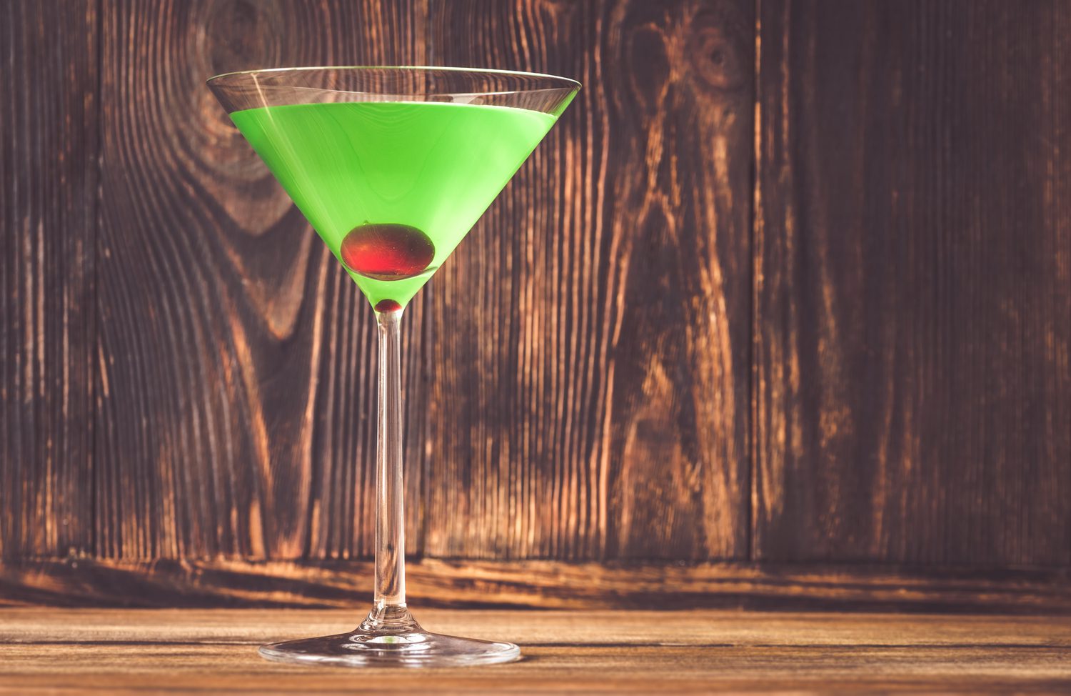 Glass of japanese slipper cocktail on wooden background